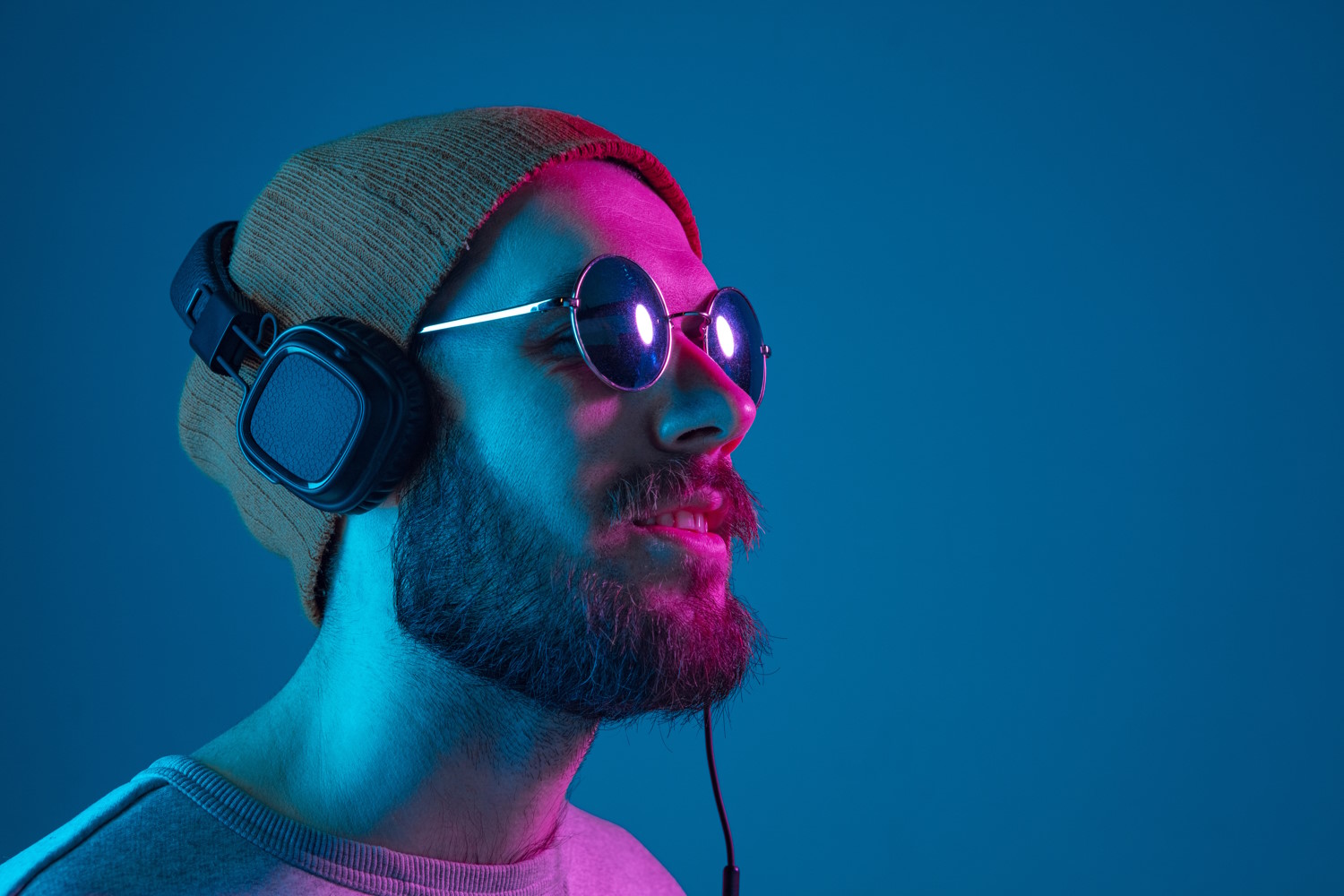 Hombre con gafas y barba escuchando música con auriculares